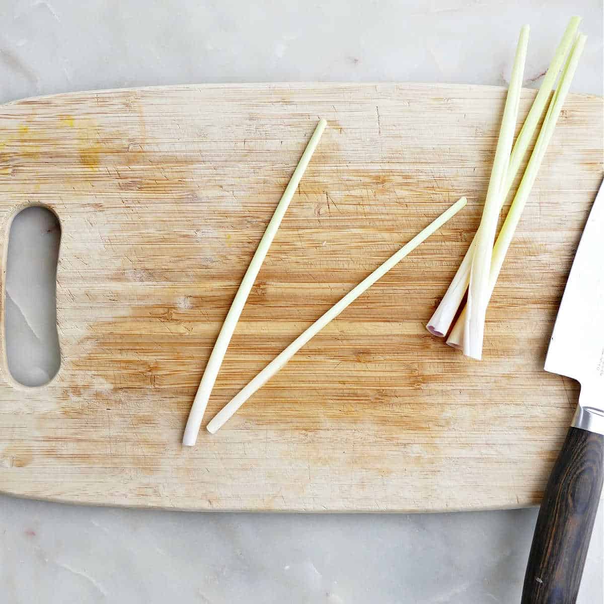 Lemongrass stalks with the outer leaves removed on a cutting board.