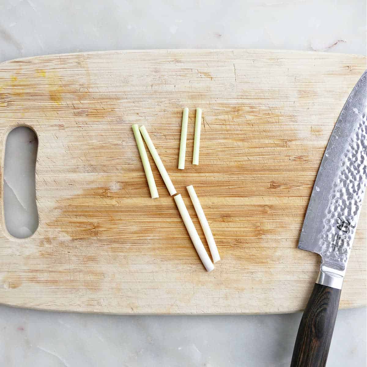 Lemongrass stalks cut into batons on a cutting board.