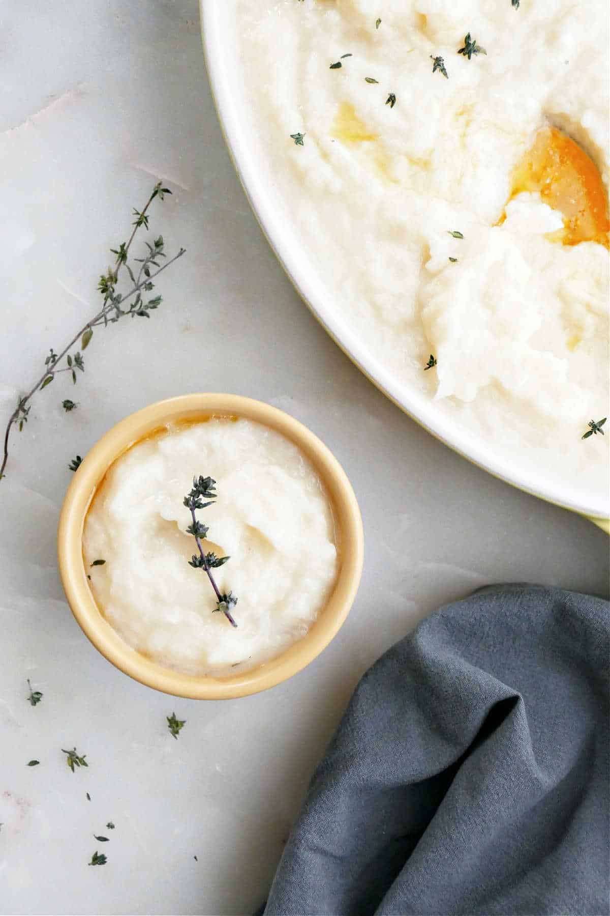 Small bowl of mashed potatoes and turnips next to serving platter with the rest.