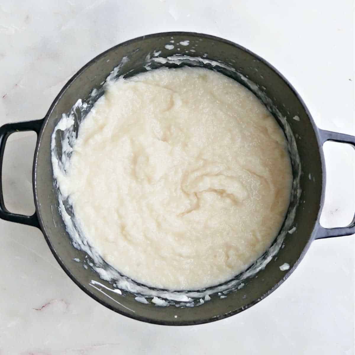 Mashed turnips and potatoes after being mixed with a hand mixer in a pot.