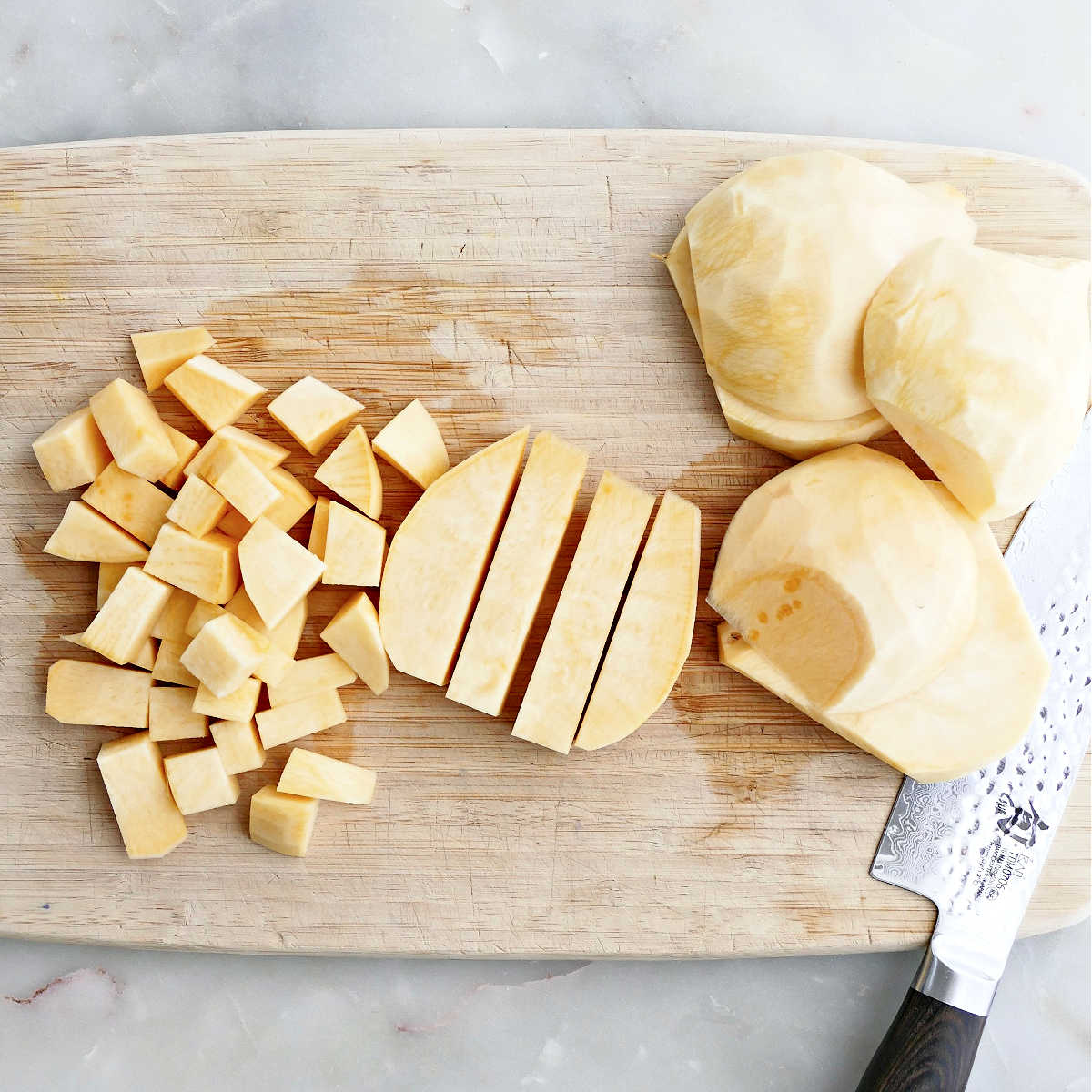 Rutabaga being cut into pieces on a cutting board.