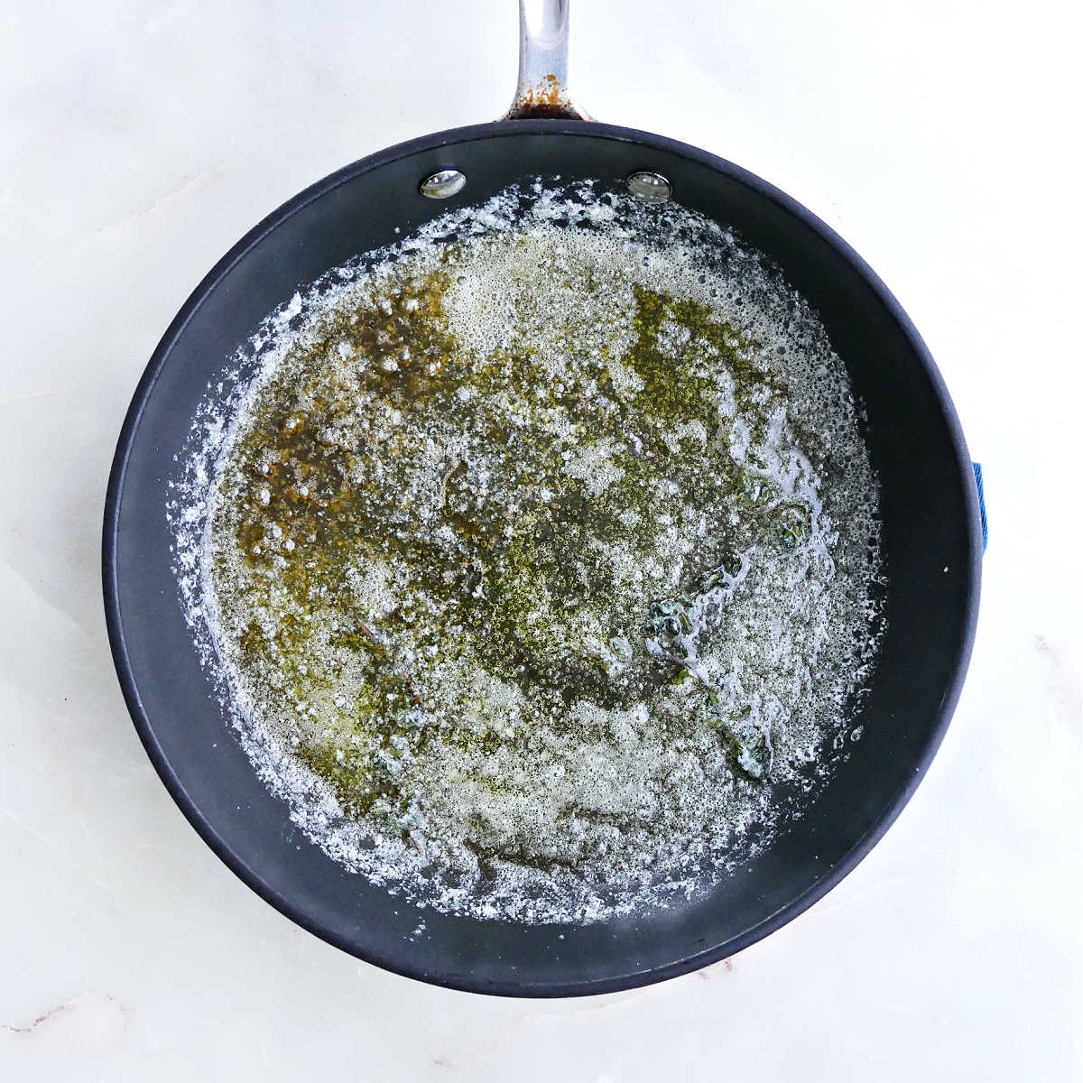 Brown butter with thyme cooking in a skillet.