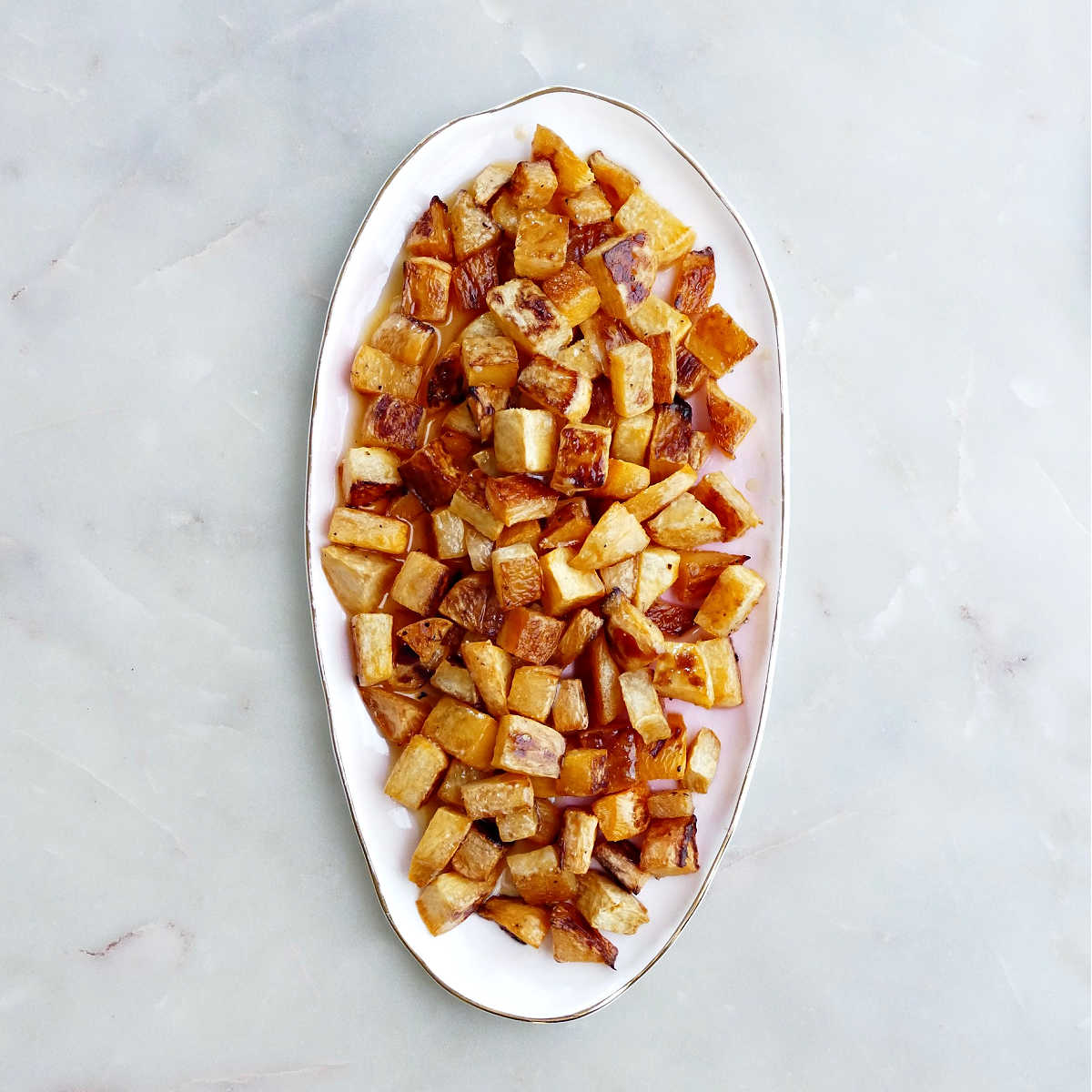 Rutabaga coated with brown butter on a serving tray.