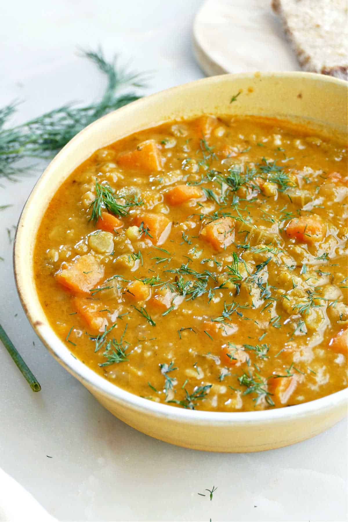 Split pea, carrot, and paprika vegan soup in a bowl on a counter.