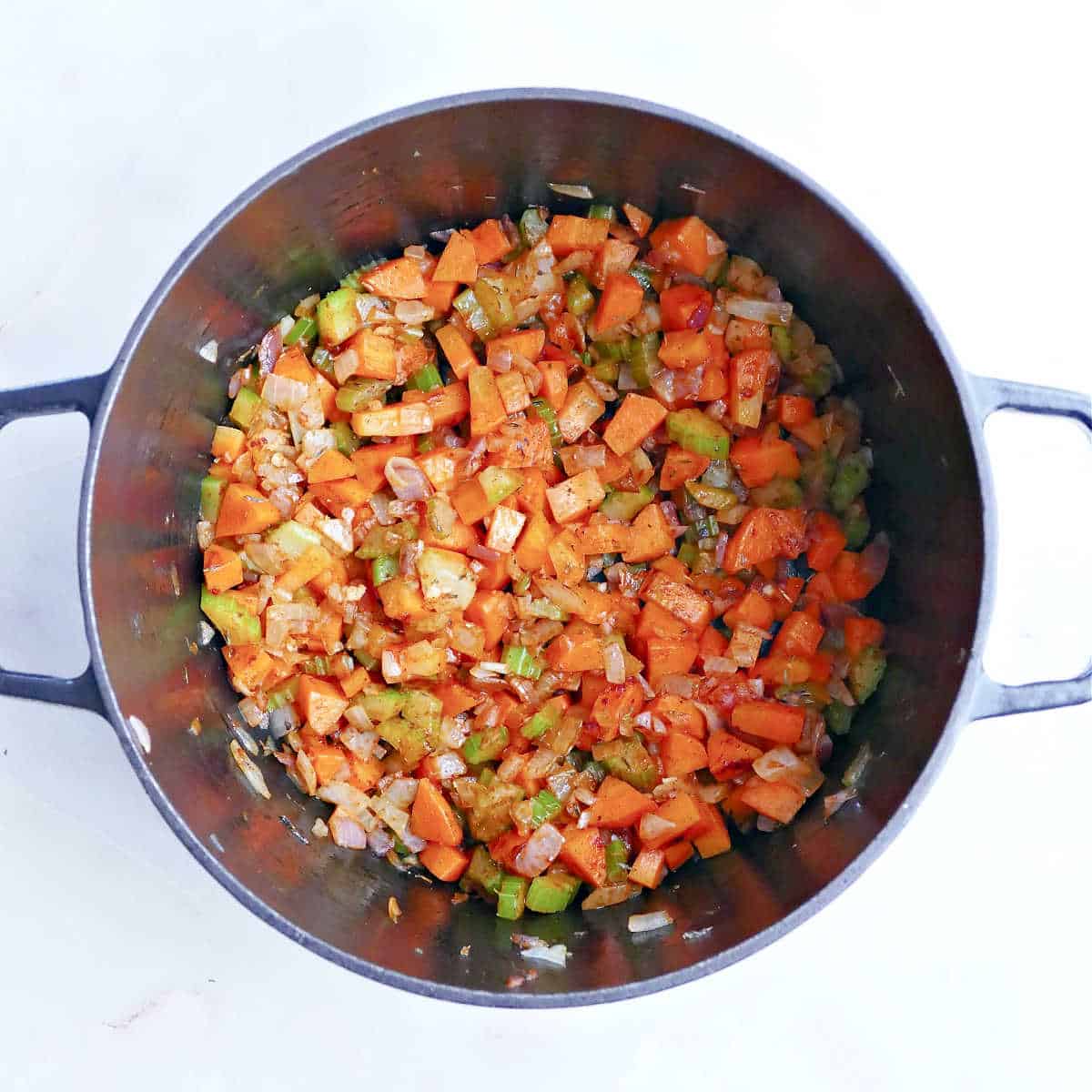 Carrots, onion, garlic, and spices cooking in a soup pot.