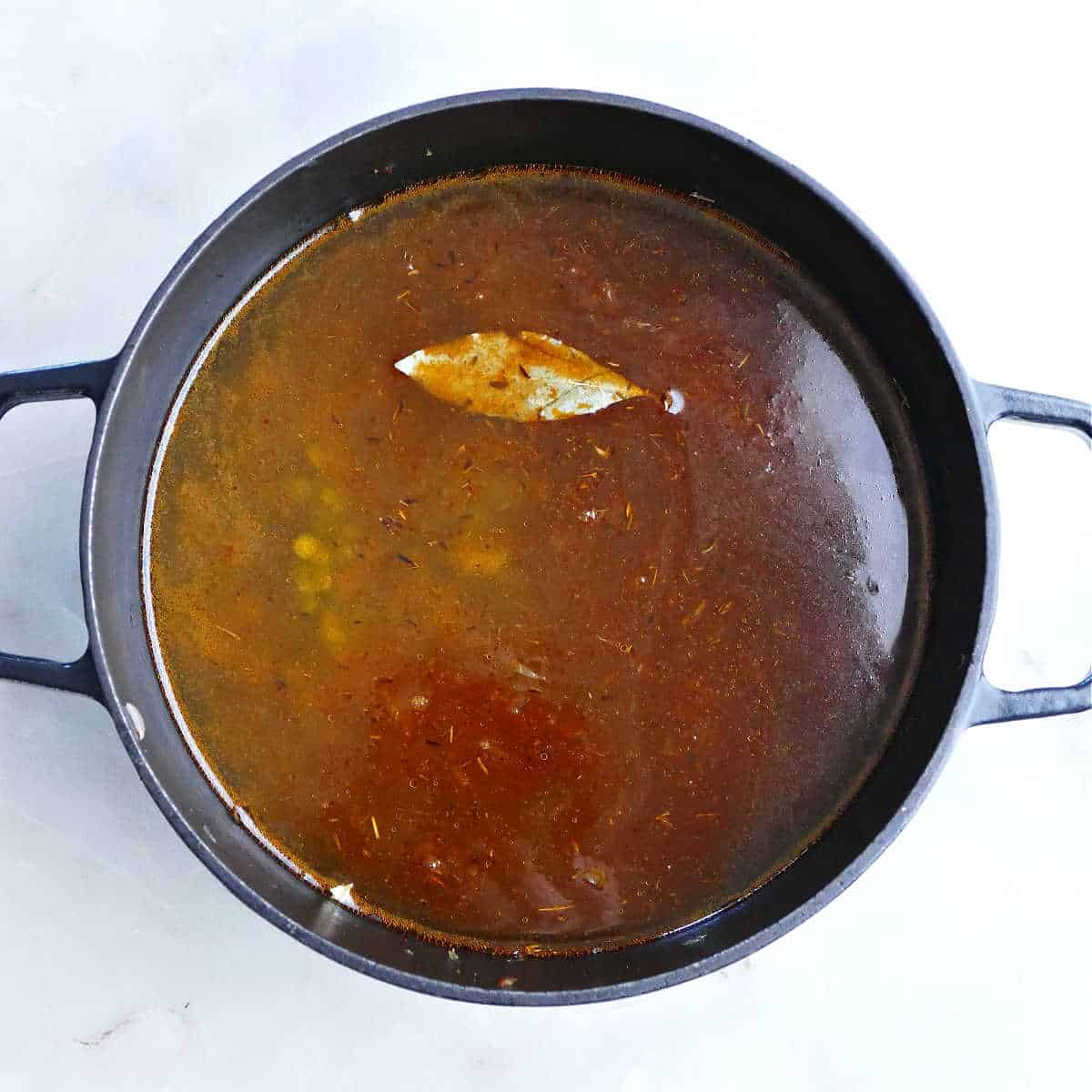 Broth and other ingredients for split peas and carrot soup in a pot.