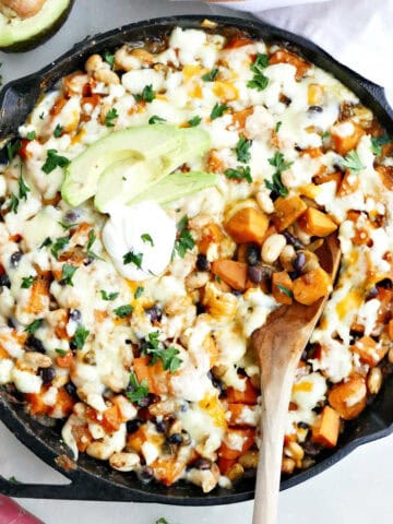 Easy sweet potato dinner in a cast iron skillet with a wooden spoon.