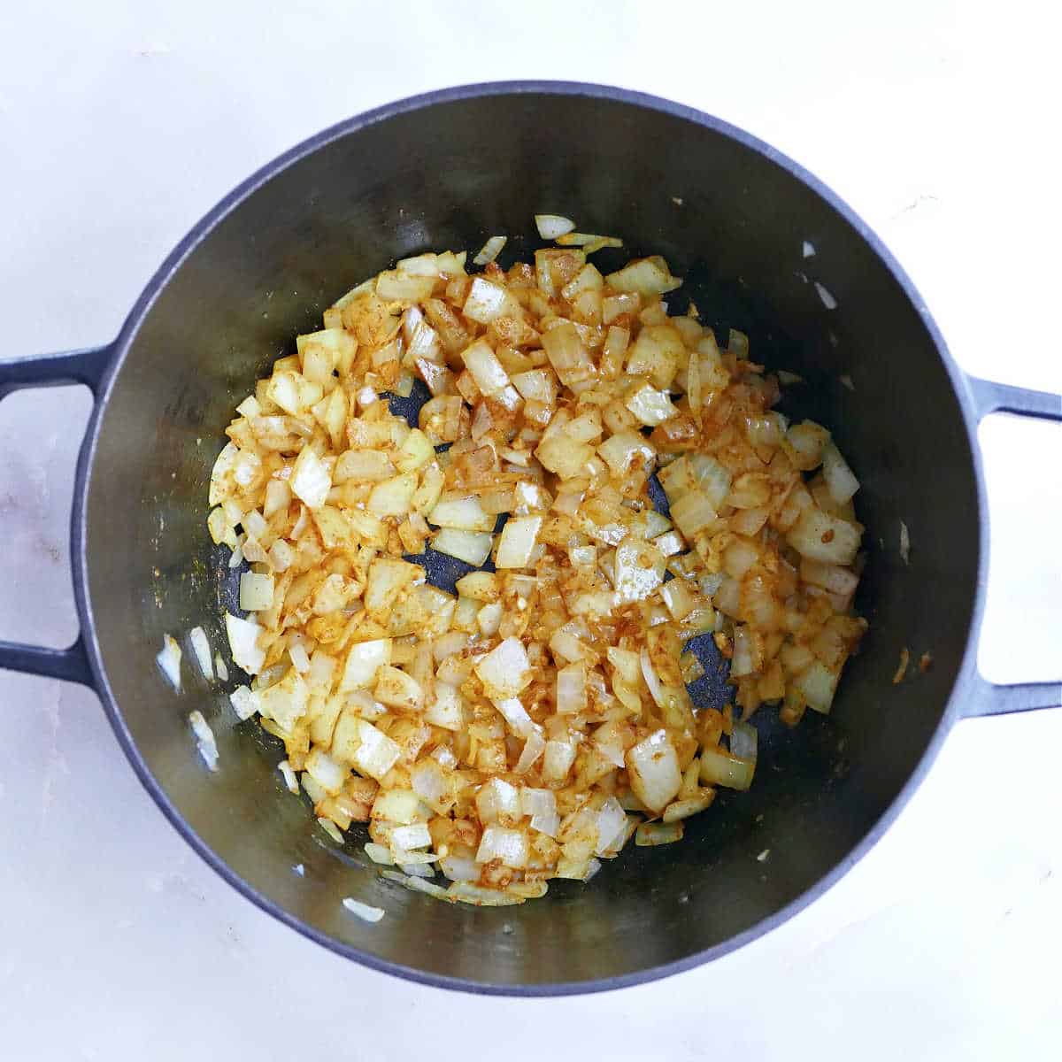 Onion, garlic, and curry powder cooking in a Dutch oven.