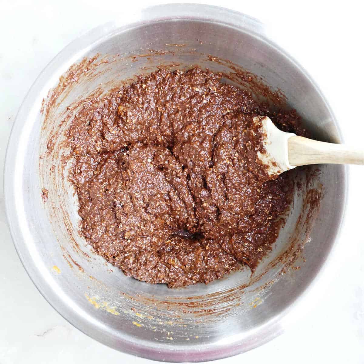 Wet and dry ingredients for almond flour cupcakes combined in a bowl with a spatula.