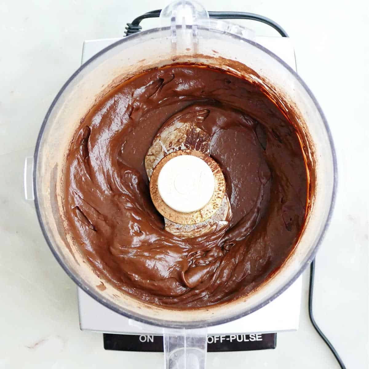 Blended avocado chocolate frosting in a food processor.