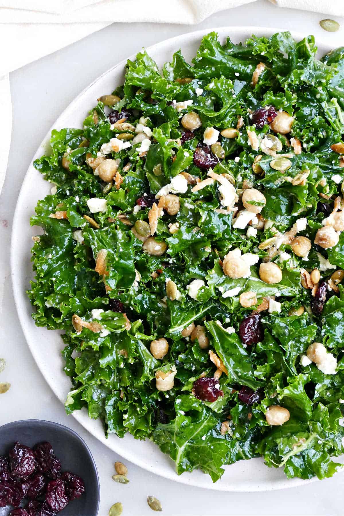 Kale and chickpea salad with feta, pumpkin seeds, and dried cherries on a plate.