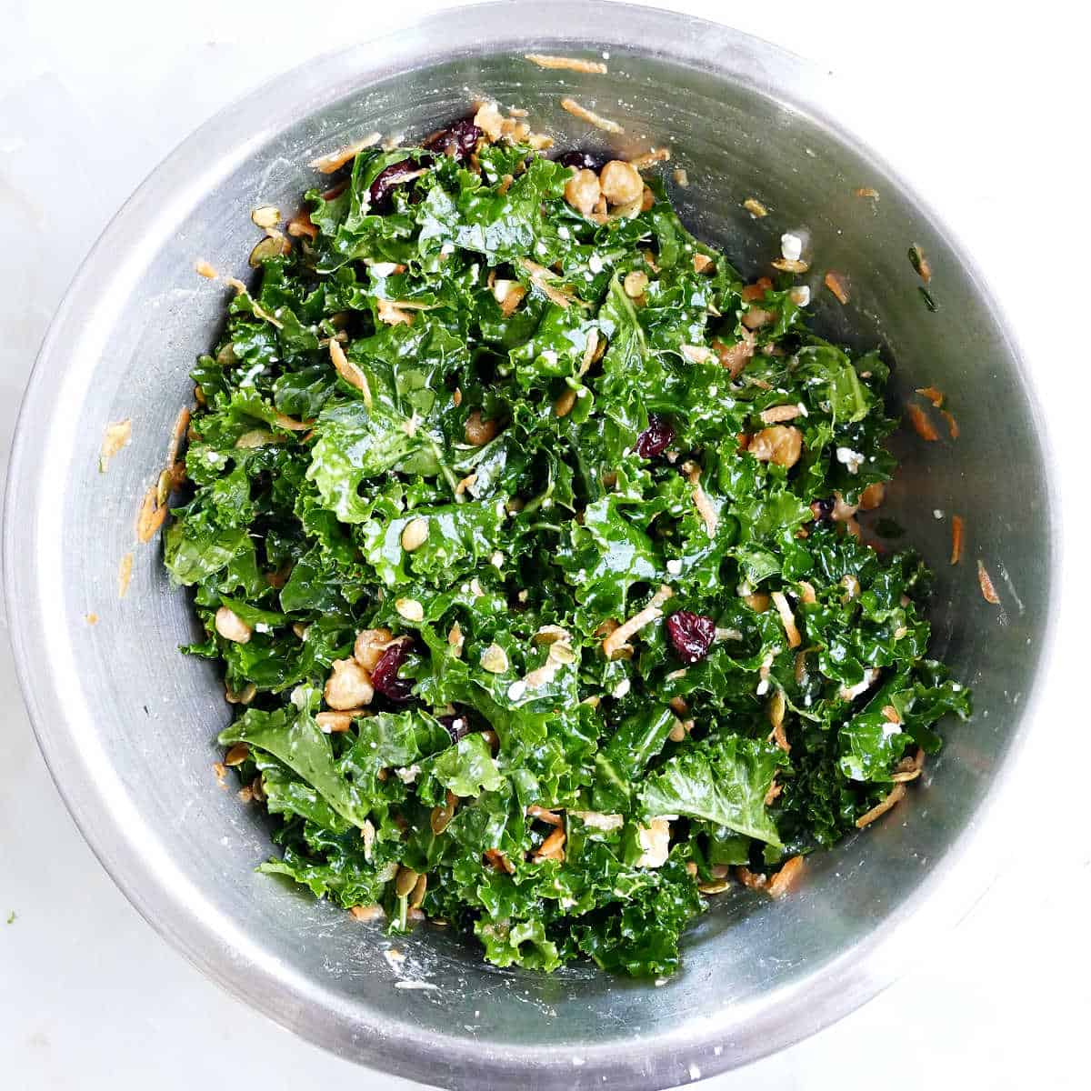 Kale and chickpea salad ingredients tossed together in a mixing bowl.