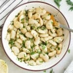 Butter beans in a bowl with a spoon next to garnishes and a napkin.