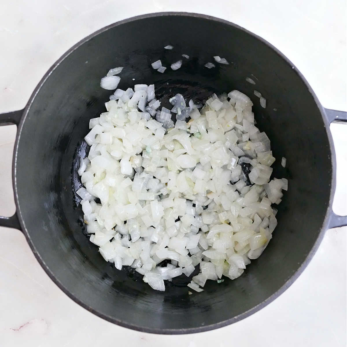 Onion and garlic cooking in olive oil in a Dutch oven.
