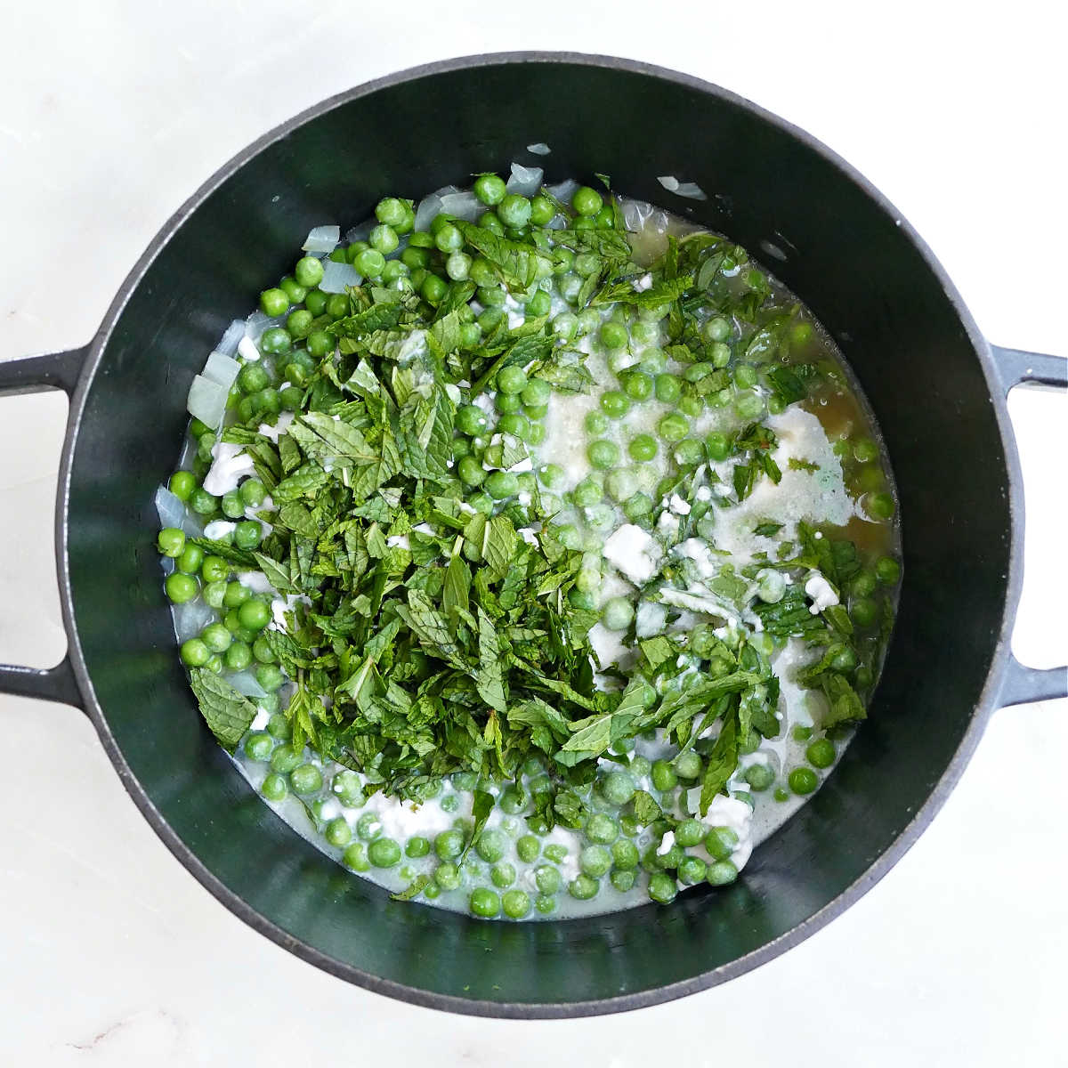 Onion, garlic, frozen peas, chopped mint, broth, and coconut milk in a Dutch oven.