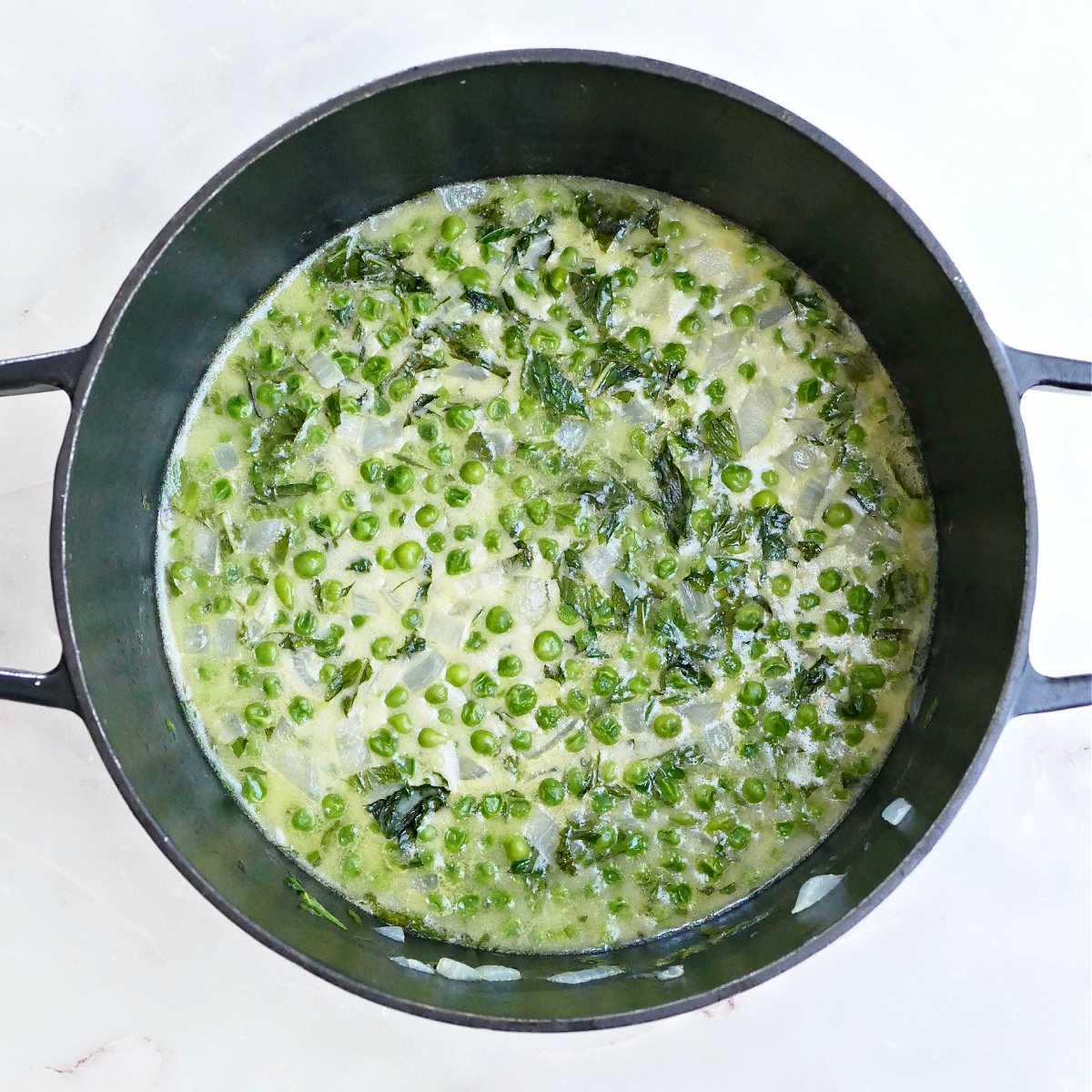 Ingredients for pea and mint soup after cooking in a Dutch oven and before blending.