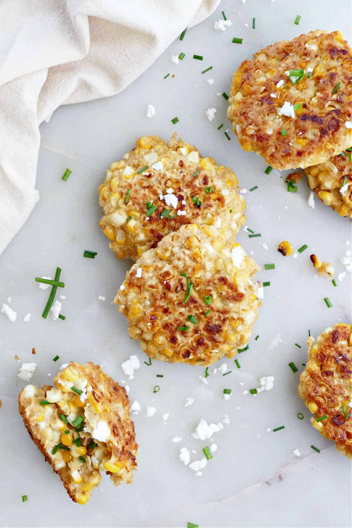 Homemade corn fritters on a what countertop sprinkled with garnish.