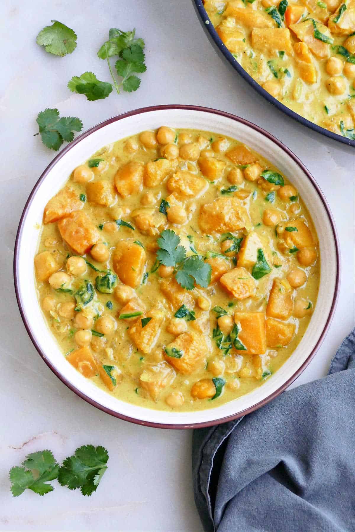 A bowl of butternut squash and chickpea curry sprinkled with herbs.