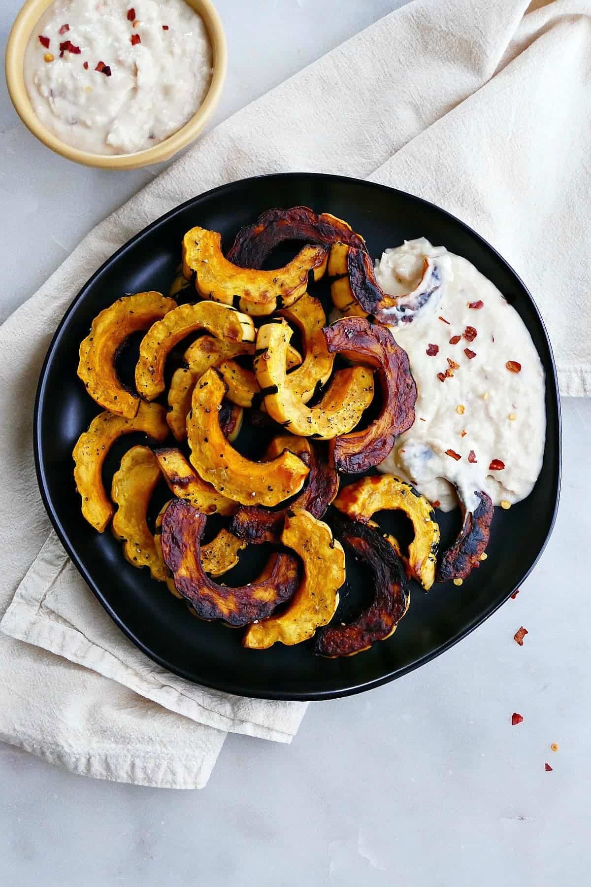 Delicata Squash Fries on a black plate with Spicy White Bean Dip. 