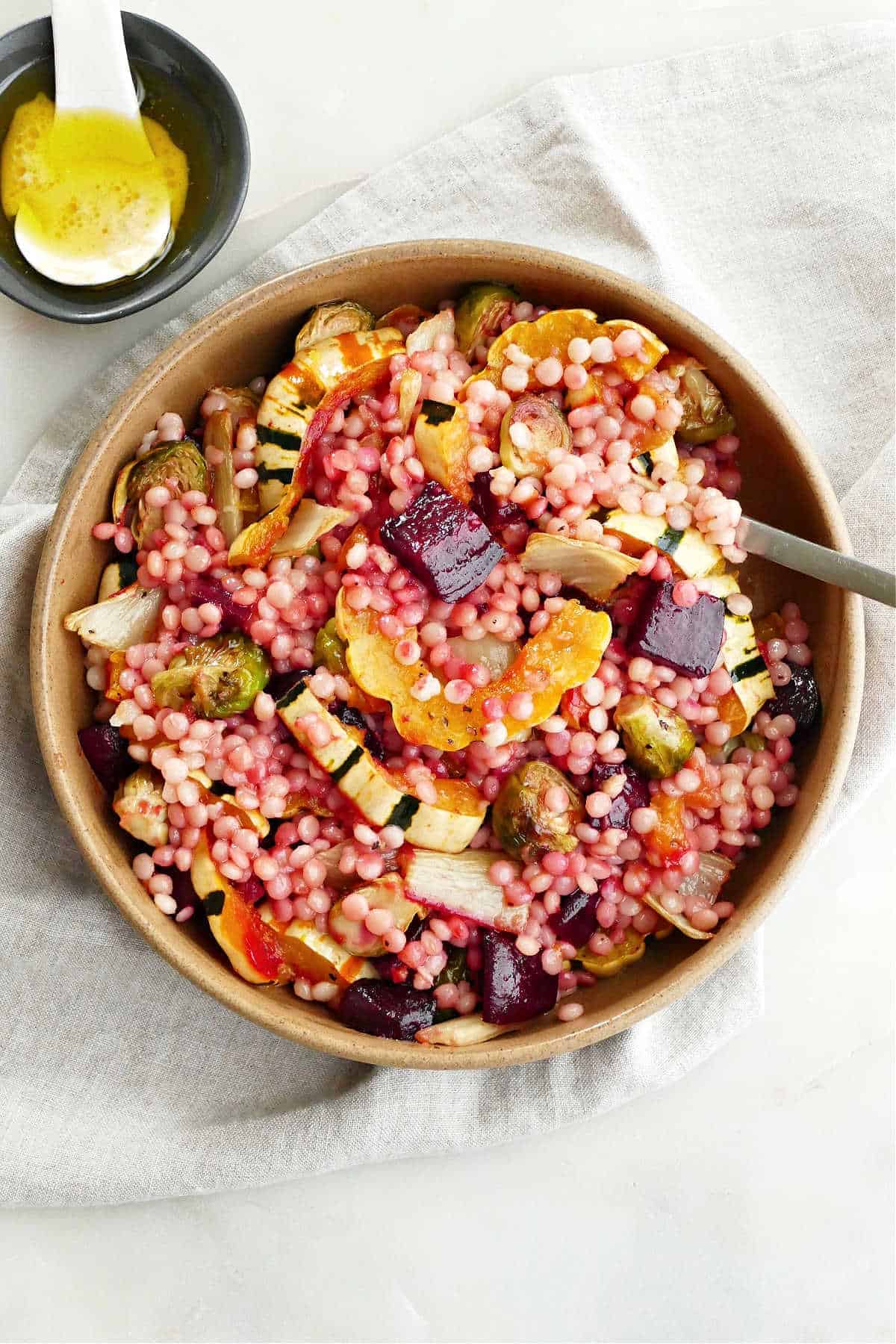 Fall Roasted Vegetable Couscous Salad on a neutral dish towel with a fork. 