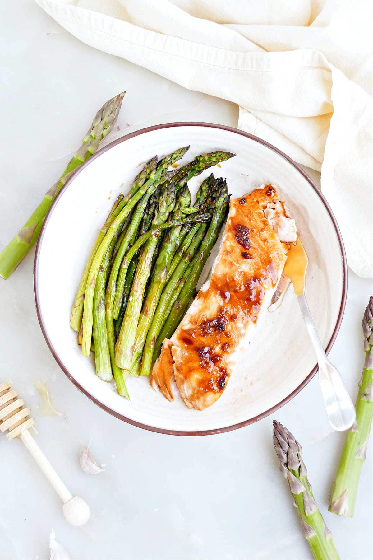 Honey glazed salmon and roasted asparagus on a plate with a fork.