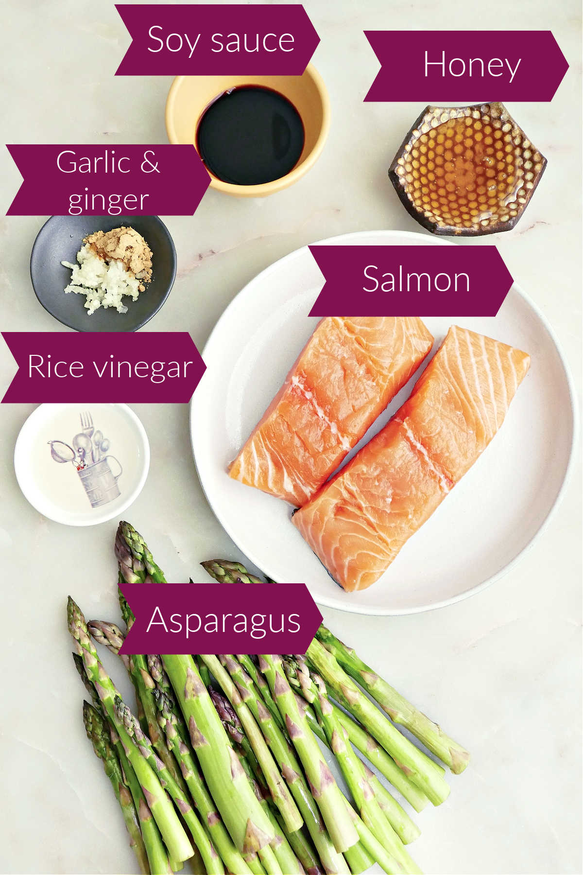 Soy sauce, honey, salmon fillets, asparagus, rice vinegar, garlic, and ginger powder on a counter with labels.