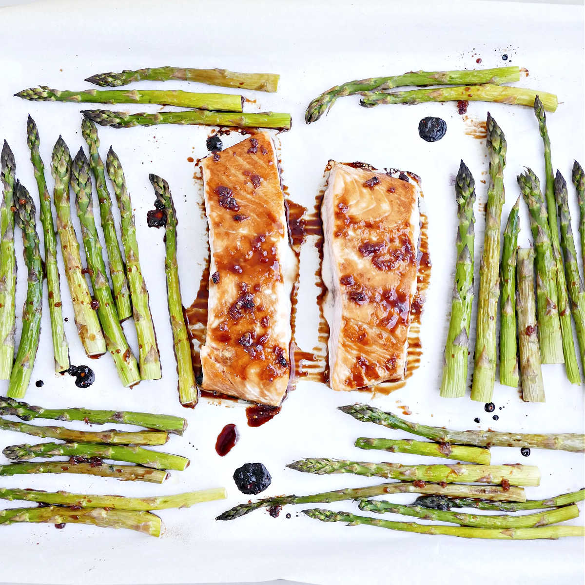 Salmon and asparagus brushed with honey glaze on a sheet pan after being baked.