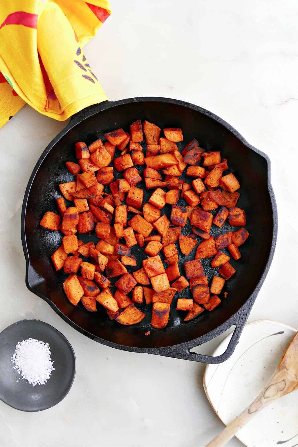 A cast iron pan filled with sauteed sweet potato cubes.