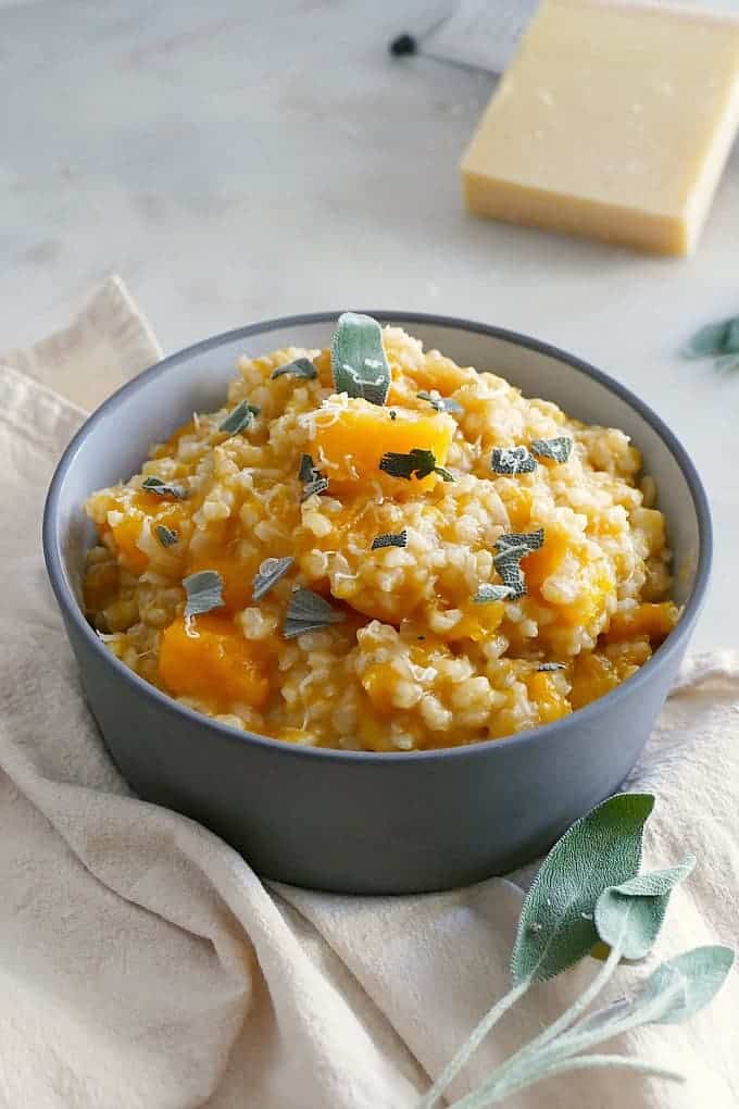 Butternut Squash Brown Rice Risotto in a blue bowl on a white kitchen towel.