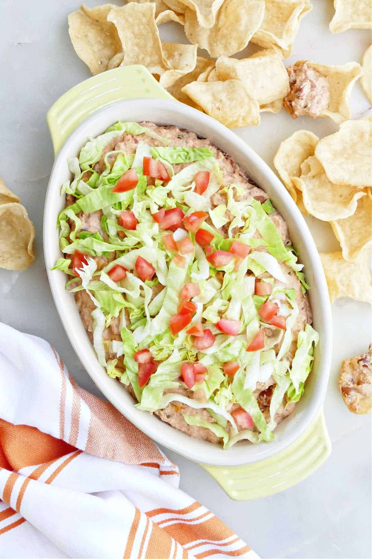 Refried bean taco dip in a dish next to tortilla chips.