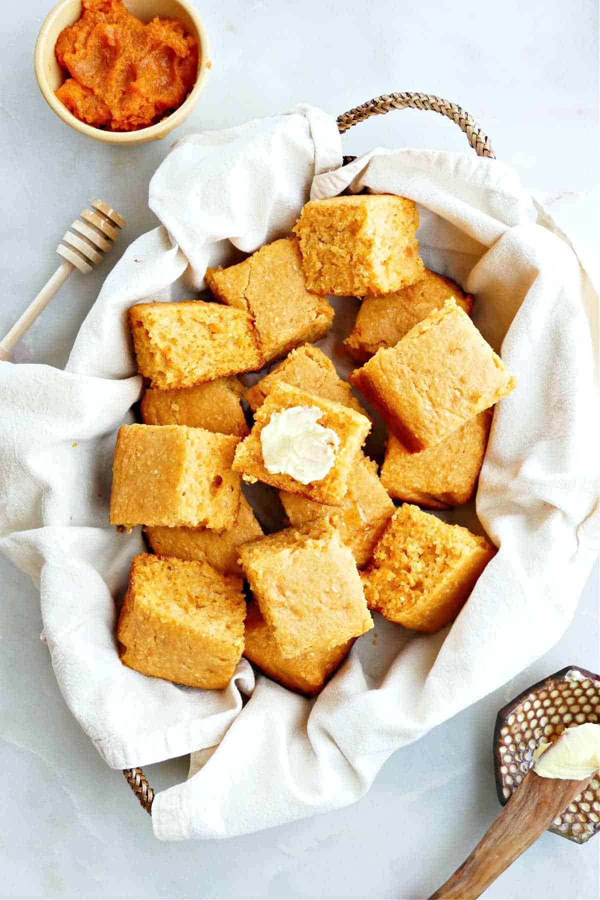 A basket of sweet potato cornbread squares next to a bowl of sweet potato puree.