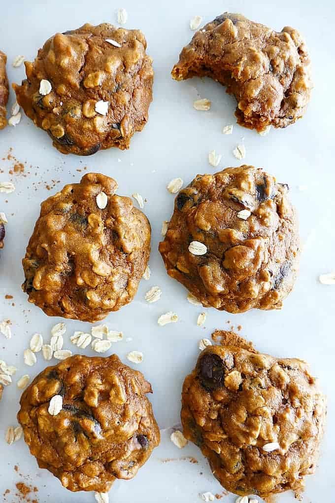 A table with oatmeal raisin sweet potato cookies on it sprinkled with oats.