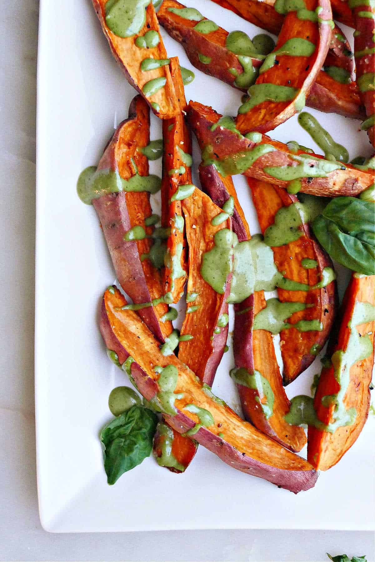 A white serving dish with basil tahini sweet potato fries on it.