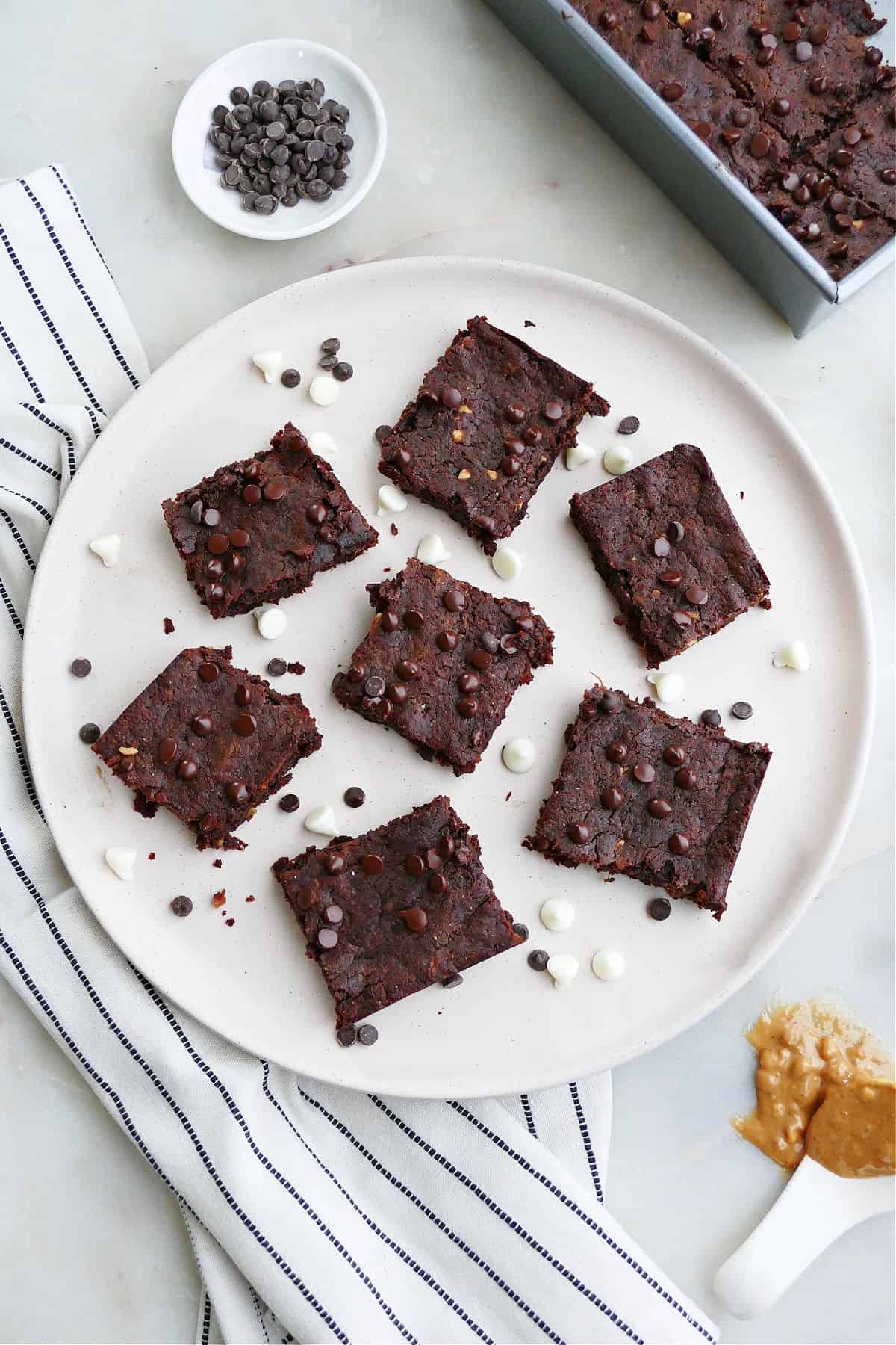 A plate of vegan sweet potato brownies sprinkled with white chocolate chips.