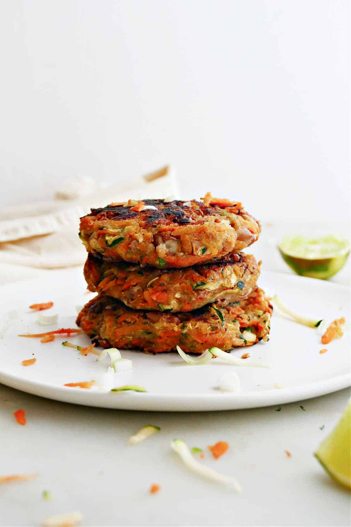 A stack of three vegan sweet potato and zucchini fritters on a plate.