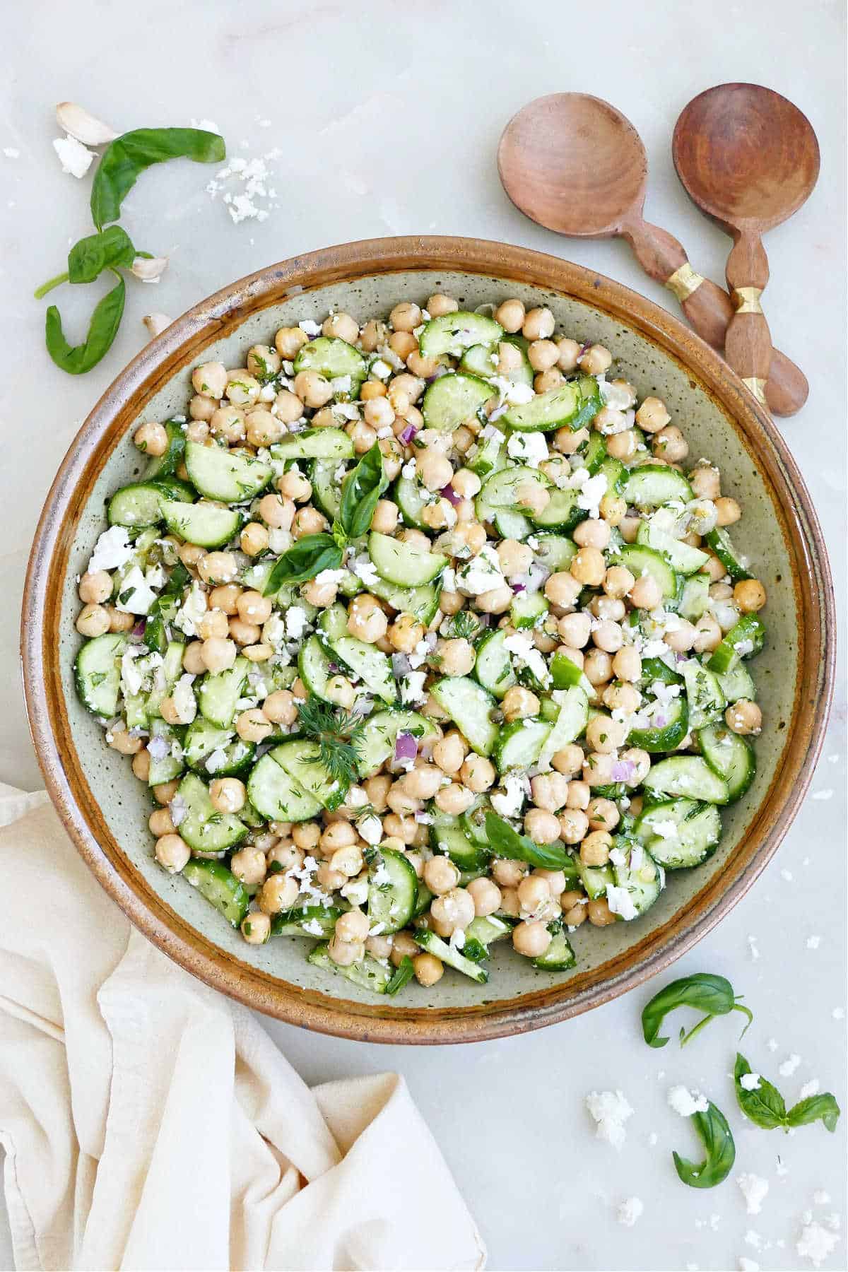 Chickpea cucumber feta salad in a mixing bowl next to napkins and utensils.