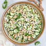 Chickpea cucumber feta salad in a mixing bowl next to napkins and utensils.