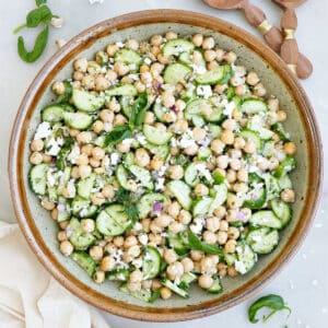 Chickpea cucumber feta salad in a mixing bowl next to napkins and utensils.