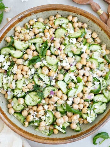 Chickpea cucumber feta salad in a mixing bowl next to napkins and utensils.