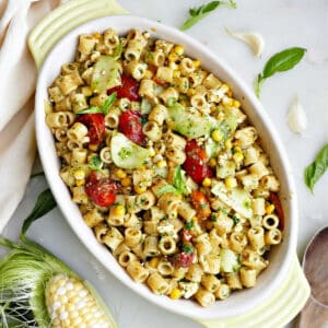 Ditalini pasta salad with summer vegetables in a yellow oval serving dish.