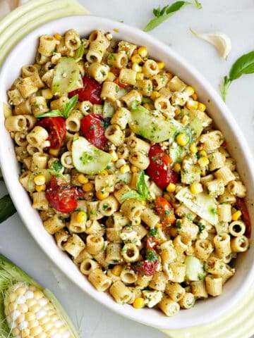 Ditalini pasta salad with summer vegetables in a yellow oval serving dish.