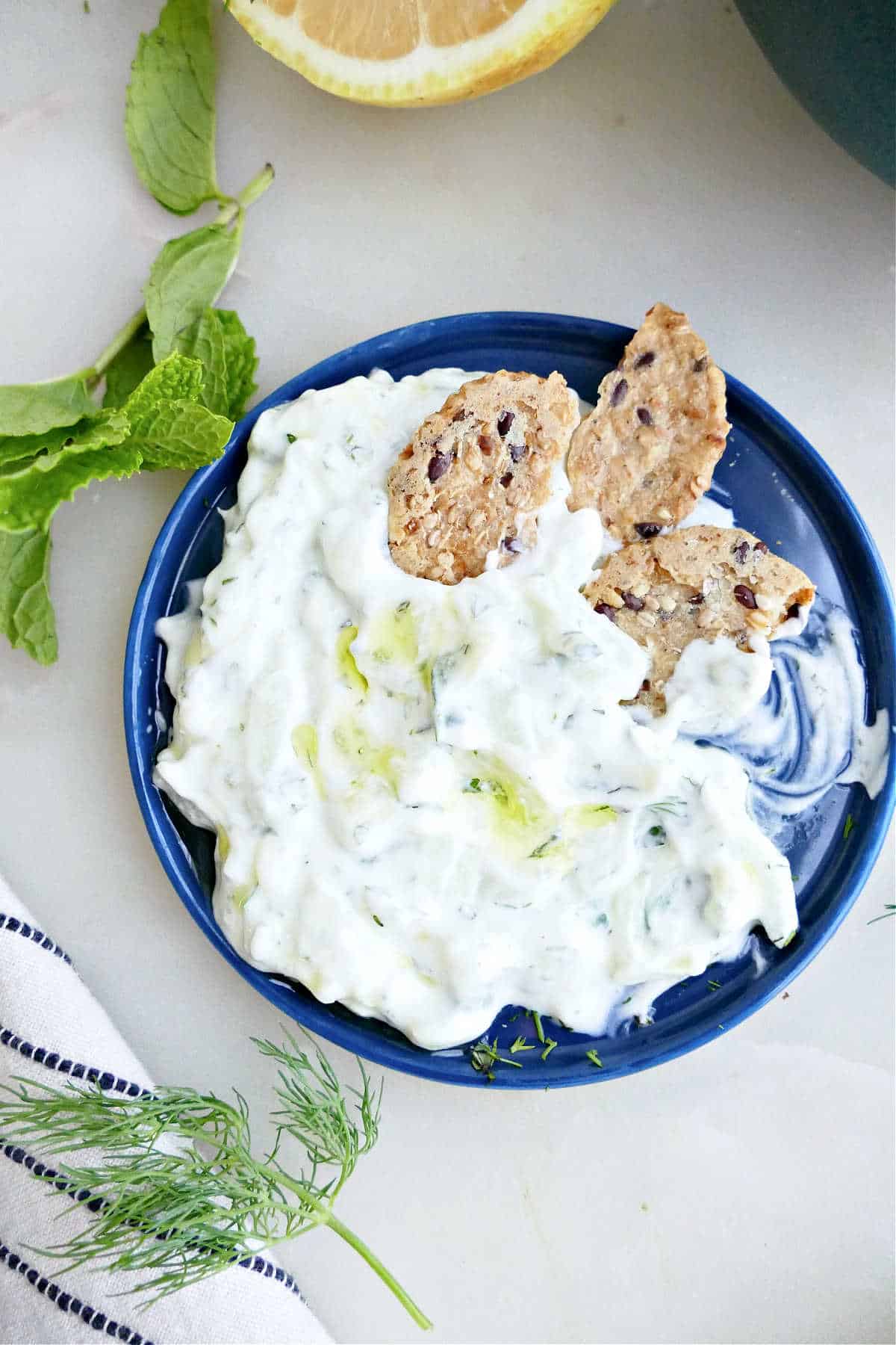 Greek yogurt cucumber sauce on a plate with seed crackers.