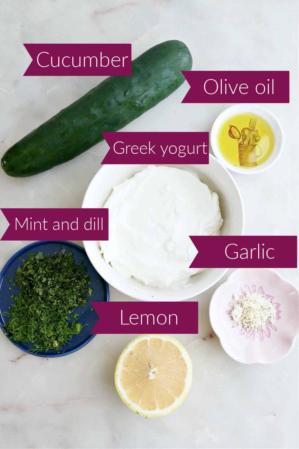 Cucumber, olive oil, Greek yogurt, garlic, lemon, and chopped herbs on a counter with labels.