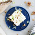 Banana zucchini cake with cream cheese frosting on a blue plate.