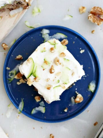 Banana zucchini cake with cream cheese frosting on a blue plate.