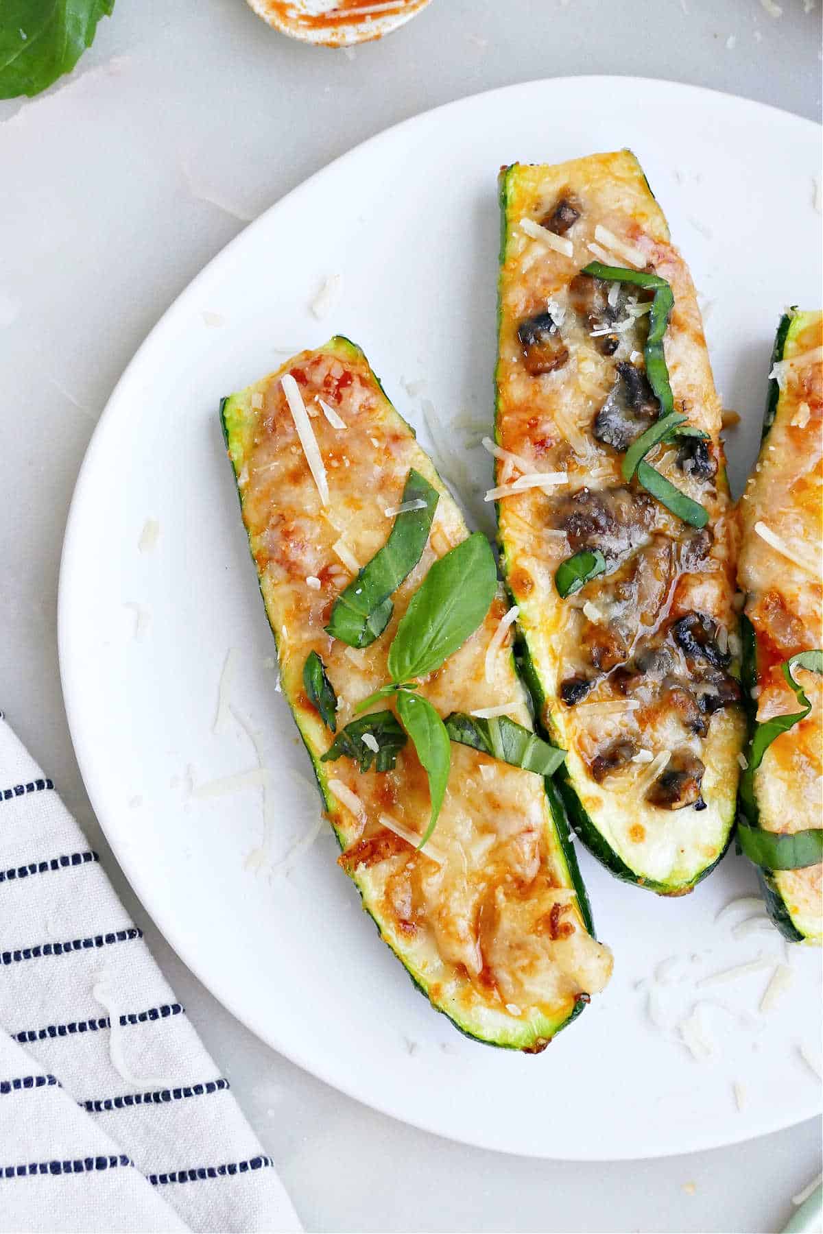 Zucchini pizza with mushrooms, peppers and onions, and basil on a plate.