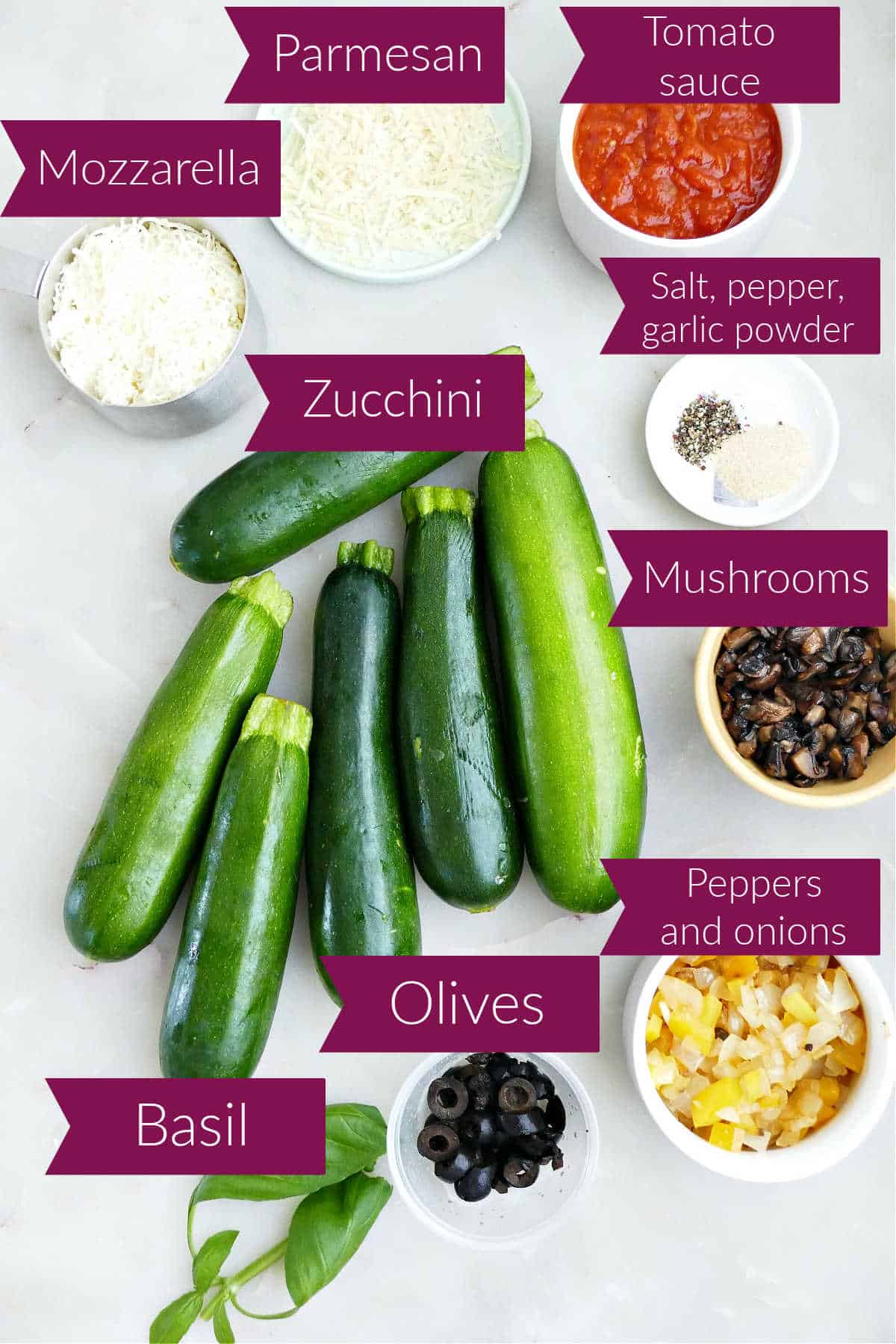Zucchini, mozzarella and parmesan cheeses, tomato sauce, spices, vegetables, olives, and basil with labels.