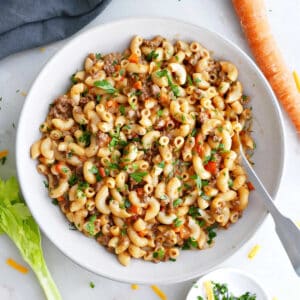Healthier hamburger helper in a serving bowl next to ingredients.