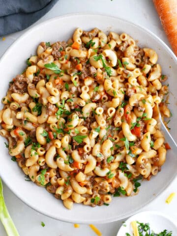 Healthier hamburger helper in a serving bowl next to ingredients.