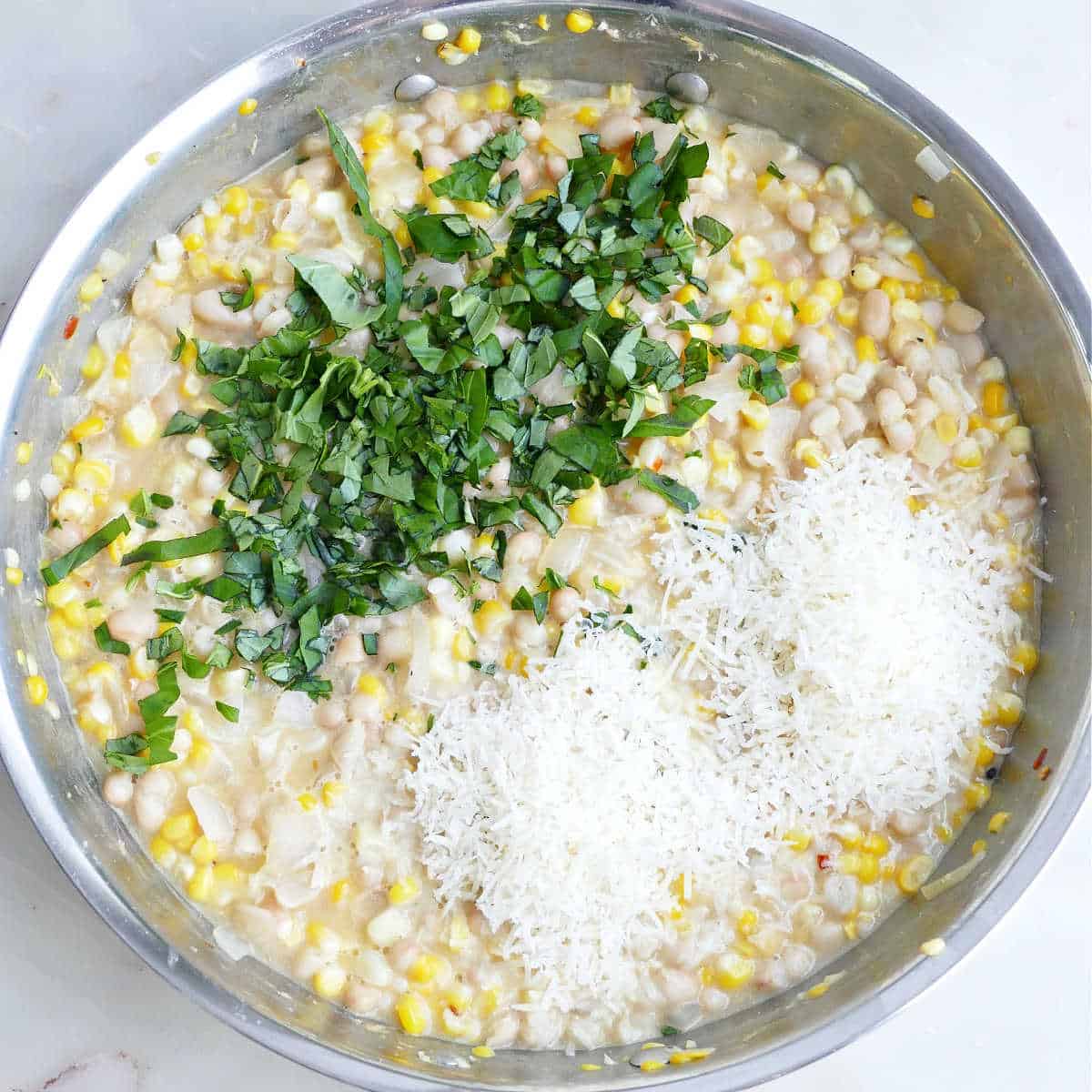 Basil and parmesan cheese added to a corn white bean skillet.
